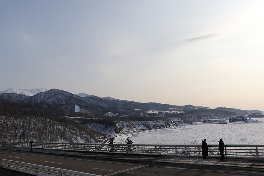 ハイヤ大橋をバックに映る鍵井さんと河本
