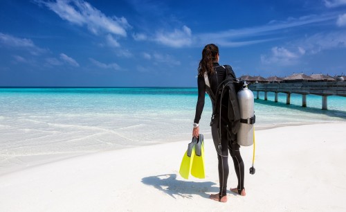 Weibliche Taucherin mit Ausrüstung am Strand der Malediven